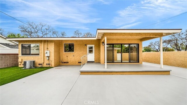 rear view of property featuring a patio, central AC unit, fence, and stucco siding