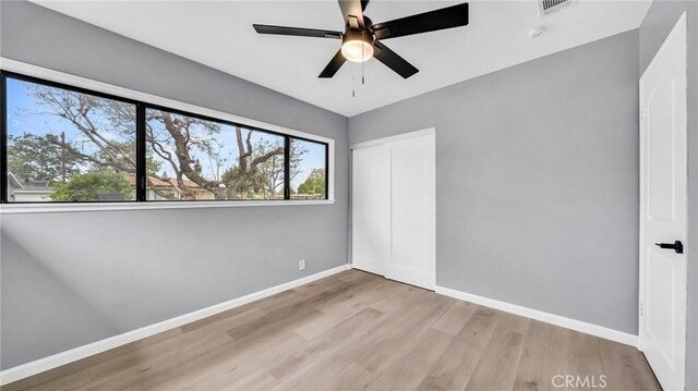 unfurnished bedroom with wood finished floors, baseboards, a closet, and ceiling fan