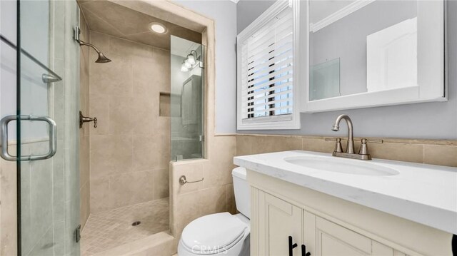 full bath featuring toilet, a stall shower, vanity, ornamental molding, and tile walls