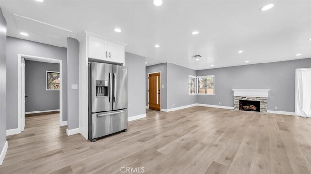 unfurnished living room featuring baseboards, light wood-style flooring, a fireplace, and recessed lighting