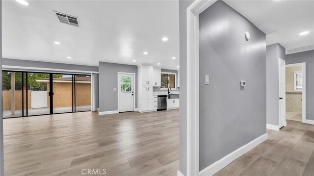 hallway with light wood-style floors, baseboards, a sink, and recessed lighting