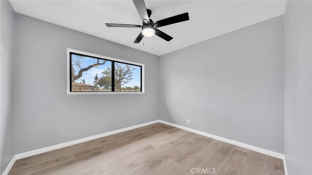 empty room with wood finished floors, baseboards, and a ceiling fan