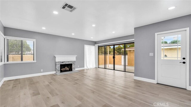 unfurnished living room with plenty of natural light, light wood-type flooring, baseboards, and recessed lighting