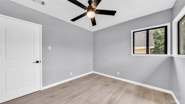 empty room featuring ceiling fan, light wood-style flooring, and baseboards
