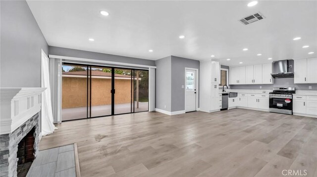 unfurnished living room featuring recessed lighting, a fireplace, light wood finished floors, and baseboards