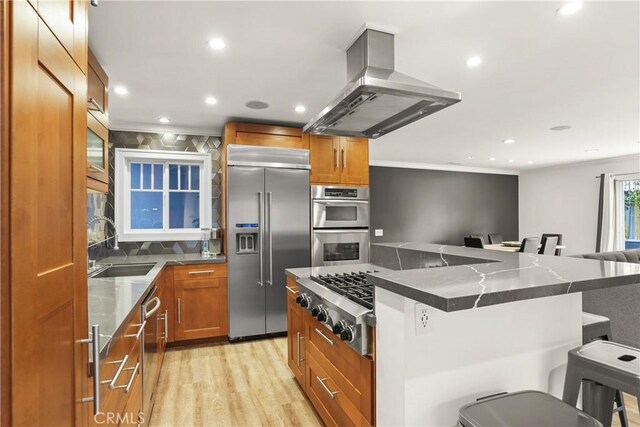 515 Traverse Dr, Costa Mesa, CA 92626 - kitchen with stainless steel appliances, island exhaust hood, a kitchen bar, a sink, and light wood-style floors