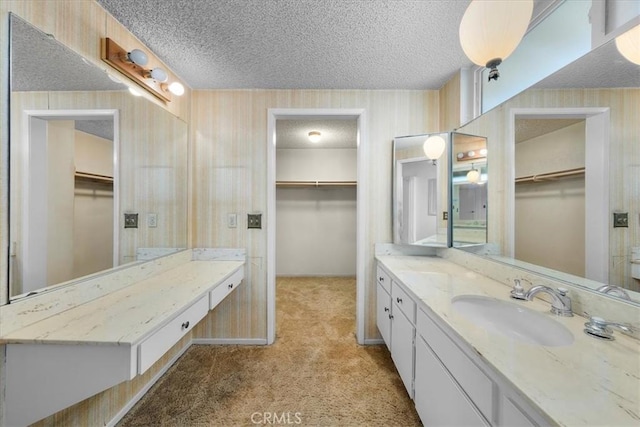 19923 Mildred Ave, Torrance, CA 90503 - bathroom featuring a textured ceiling, vanity, wallpapered walls, a spacious closet, and baseboards
