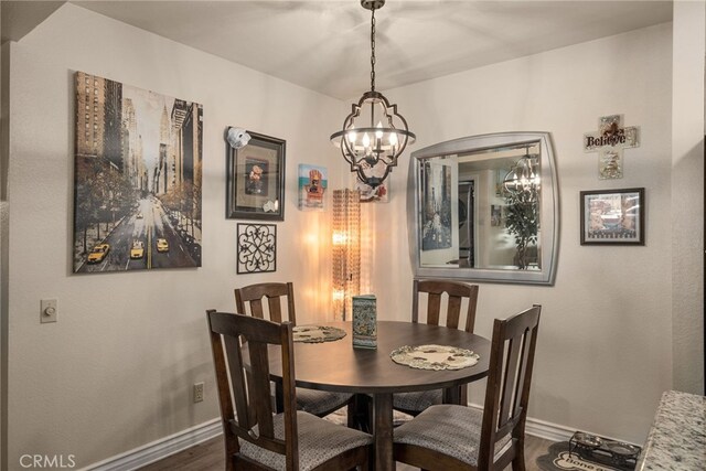 dining area featuring baseboards, dark wood finished floors, and a chandelier