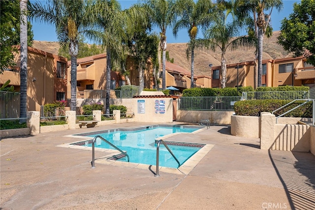 community pool with fence, a patio area, a residential view, and a mountain view