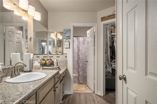 full bathroom with wood finished floors, vanity, toilet, curtained shower, and a walk in closet
