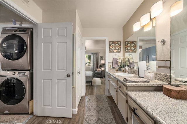 bathroom with stacked washer and clothes dryer, wood finished floors, vanity, and connected bathroom