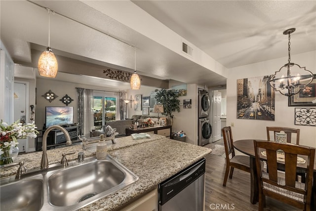 kitchen featuring stacked washer / drying machine, a sink, stainless steel dishwasher, wood finished floors, and open floor plan