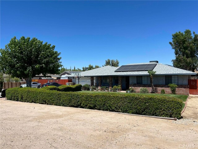 7477 Corona Ave, Hesperia, CA 92345 - view of front of house featuring roof mounted solar panels, fence, and brick siding