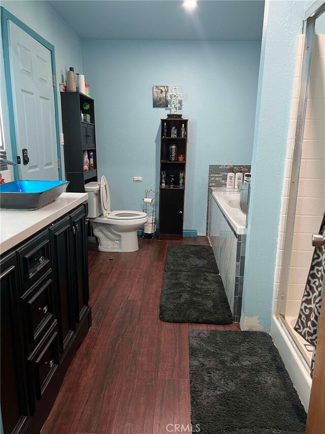 7477 Corona Ave, Hesperia, CA 92345 - bathroom with wood finished floors, toilet, tiled bath, a shower, and vanity