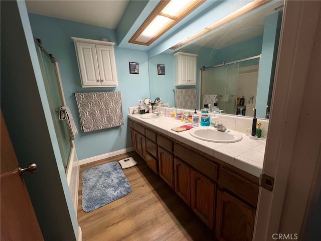 7477 Corona Ave, Hesperia, CA 92345 - bathroom with a shower stall, wood finished floors, double vanity, and baseboards