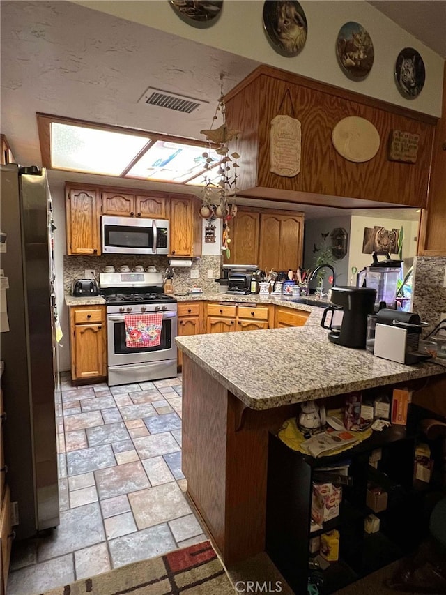 7477 Corona Ave, Hesperia, CA 92345 - kitchen featuring appliances with stainless steel finishes, stone tile flooring, a peninsula, light countertops, and a sink