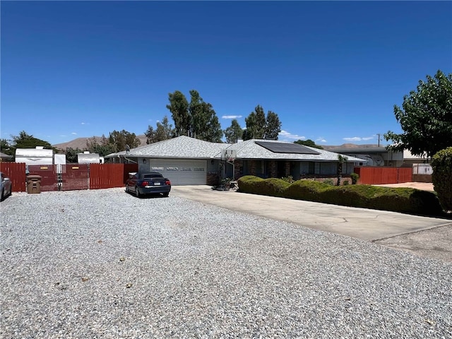 7477 Corona Ave, Hesperia, CA 92345 - single story home featuring an attached garage, roof mounted solar panels, driveway, fence, and a mountain view