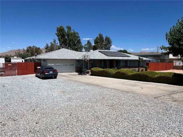 7477 Corona Ave, Hesperia, CA 92345 - single story home featuring concrete driveway, solar panels, an attached garage, fence, and a mountain view