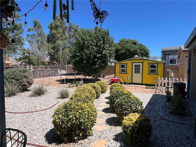 7477 Corona Ave, Hesperia, CA 92345 - view of yard featuring fence, an outbuilding, a trampoline, and cooling unit