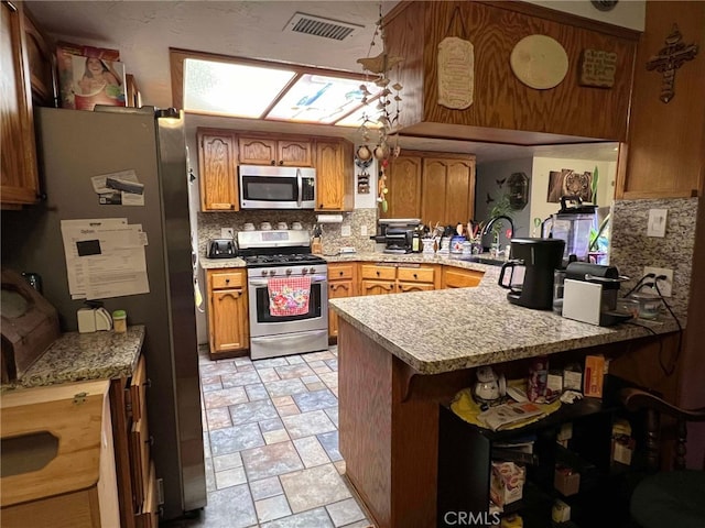7477 Corona Ave, Hesperia, CA 92345 - kitchen with stainless steel appliances, a peninsula, a sink, decorative backsplash, and stone finish floors