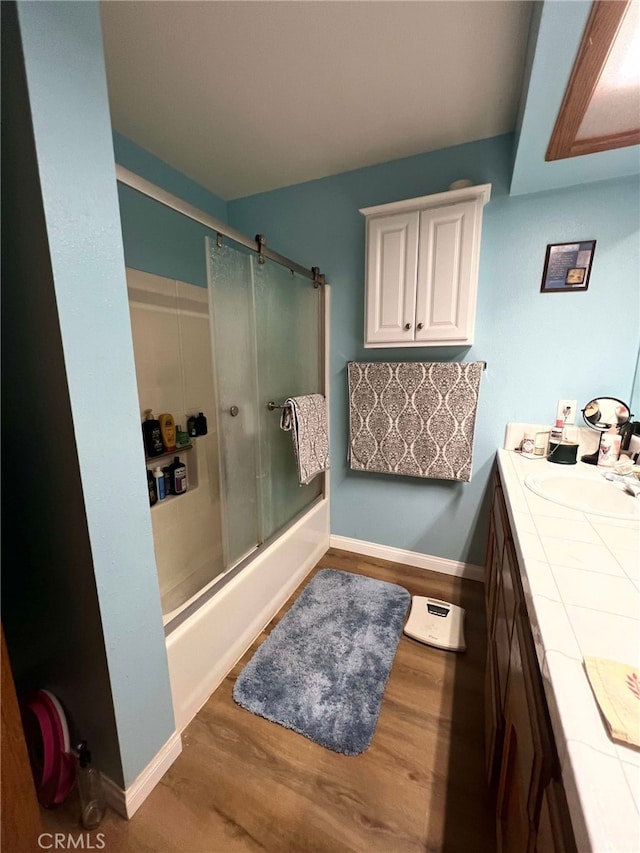 7477 Corona Ave, Hesperia, CA 92345 - bathroom featuring wood finished floors, bath / shower combo with glass door, vanity, and baseboards