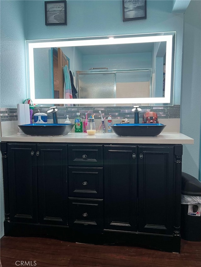 7477 Corona Ave, Hesperia, CA 92345 - full bathroom with double vanity, tasteful backsplash, wood finished floors, and a shower with door