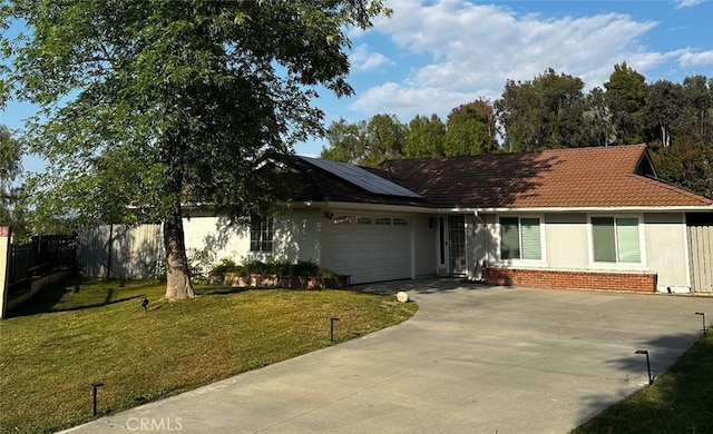 ranch-style house with a garage, roof mounted solar panels, concrete driveway, and a tile roof