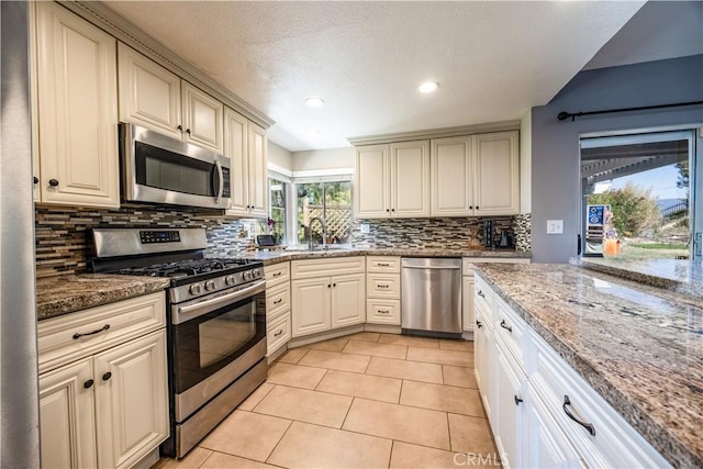 30681 Southern Cross Rd, Temecula, CA 92592 - kitchen with stainless steel appliances, cream cabinetry, decorative backsplash, light tile patterned floors, and stone countertops