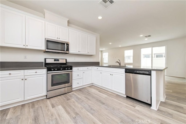 5961 Silveira St, Eastvale, CA 92880 - kitchen featuring stainless steel appliances, light wood-style flooring, a peninsula, a sink, and white cabinetry
