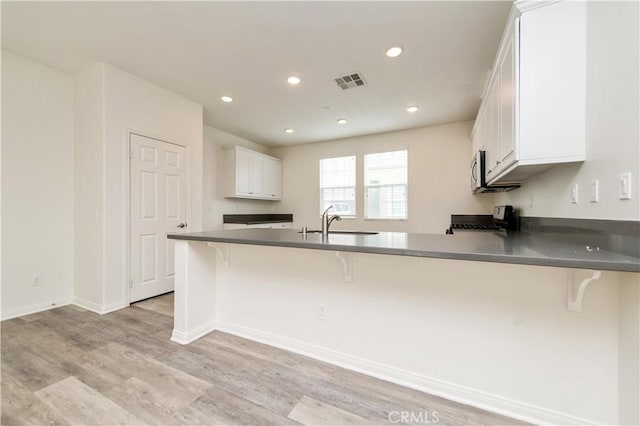 5961 Silveira St, Eastvale, CA 92880 - kitchen with range, light wood-style flooring, a peninsula, a sink, and a breakfast bar area