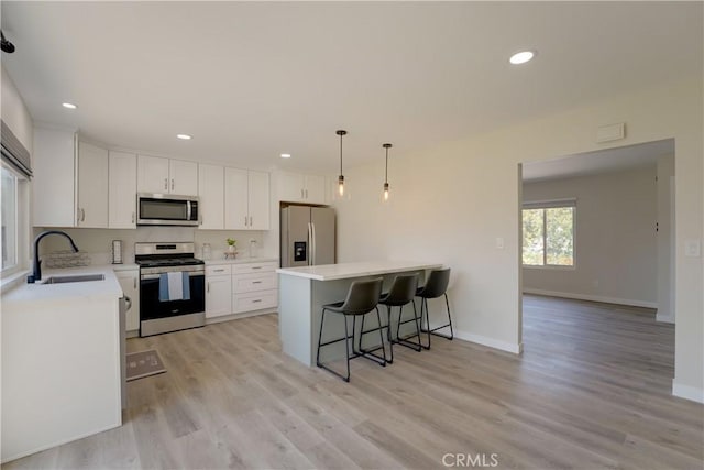 10319 Hemphill Ct, San Diego, CA 92126 - kitchen featuring stainless steel appliances, a sink, a breakfast bar, white cabinets, and a peninsula
