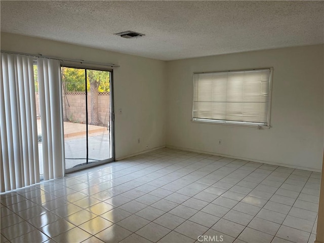 spare room with light tile patterned flooring and a textured ceiling