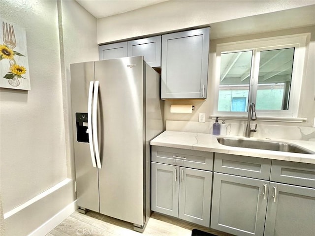 738 N Fairhaven St, Anaheim, CA 92801 - kitchen with stainless steel fridge with ice dispenser, gray cabinets, a sink, light wood-style flooring, and light stone counters
