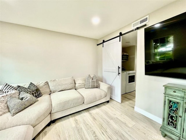 738 N Fairhaven St, Anaheim, CA 92801 - living room with a barn door, light wood-style flooring, baseboards, and independent washer and dryer