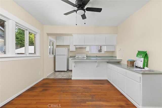 1810 Park St, Paso Robles, CA 93446 - kitchen featuring freestanding refrigerator, a peninsula, white cabinets, wood finished floors, and electric stove