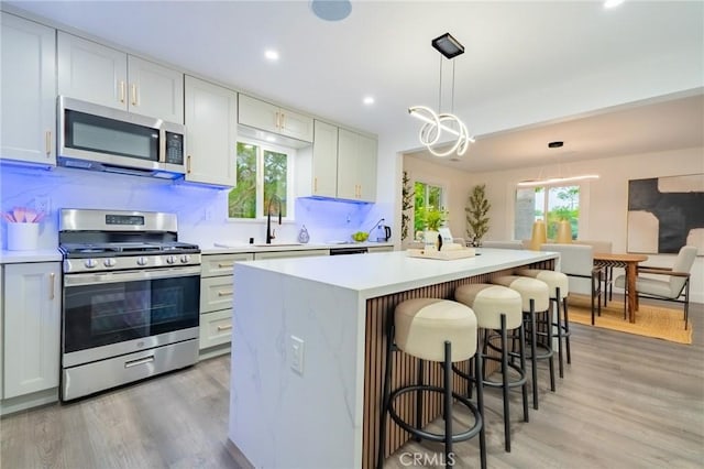 kitchen with stainless steel appliances, a center island, light countertops, light wood-style floors, and healthy amount of natural light