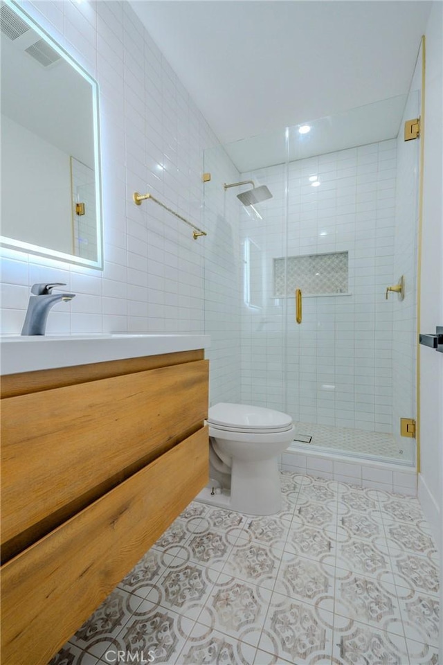 full bathroom with tile patterned flooring, toilet, a shower stall, vanity, and tile walls