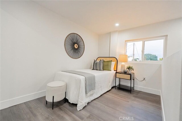 bedroom featuring wood finished floors, baseboards, and recessed lighting