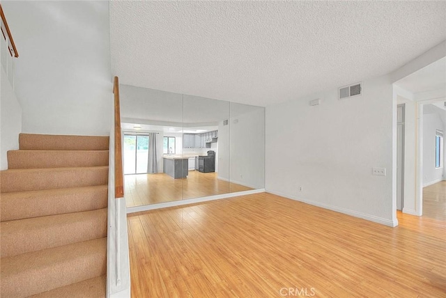 1207 Porto Grande Unit 1, Diamond Bar, CA 91765 - unfurnished living room featuring light wood-style flooring, stairway, a textured ceiling, and baseboards