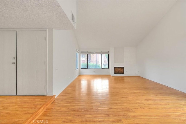 1207 Porto Grande Unit 1, Diamond Bar, CA 91765 - unfurnished living room with light wood finished floors, vaulted ceiling, a brick fireplace, and baseboards