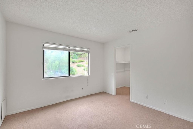 1207 Porto Grande Unit 1, Diamond Bar, CA 91765 - unfurnished bedroom with light colored carpet, a textured ceiling, a walk in closet, and baseboards