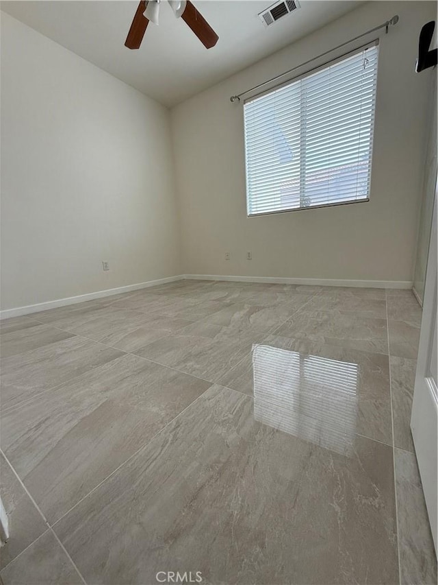 spare room featuring ceiling fan and baseboards