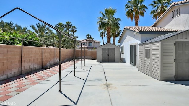 view of patio with a storage shed, a fenced backyard, and an outbuilding
