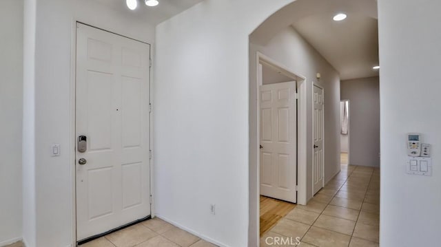 foyer entrance featuring arched walkways, light tile patterned floors, and recessed lighting