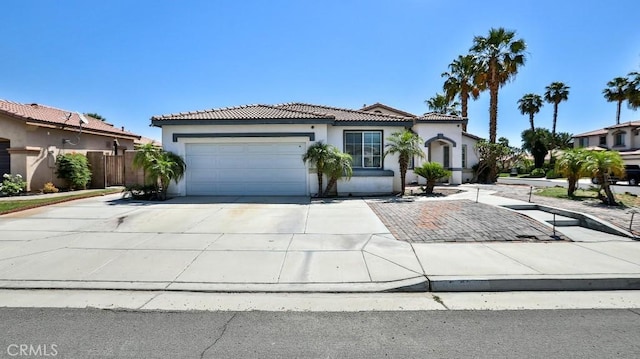 mediterranean / spanish house featuring a tiled roof, stucco siding, concrete driveway, and a garage