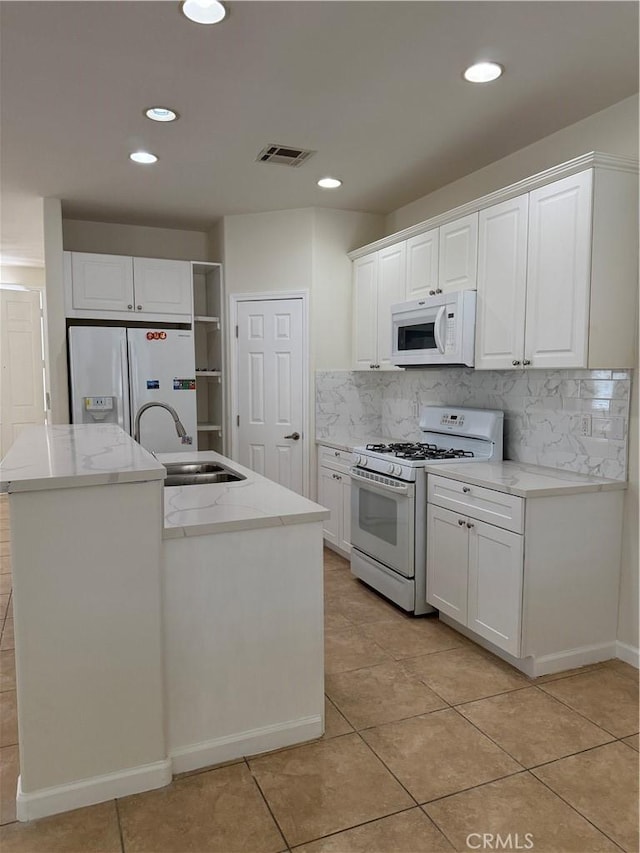 kitchen featuring white appliances, a sink, light tile patterned floors, white cabinets, and recessed lighting