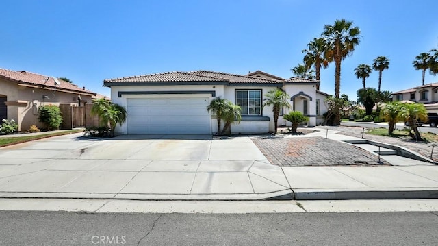 mediterranean / spanish-style house with a tiled roof, stucco siding, driveway, and an attached garage