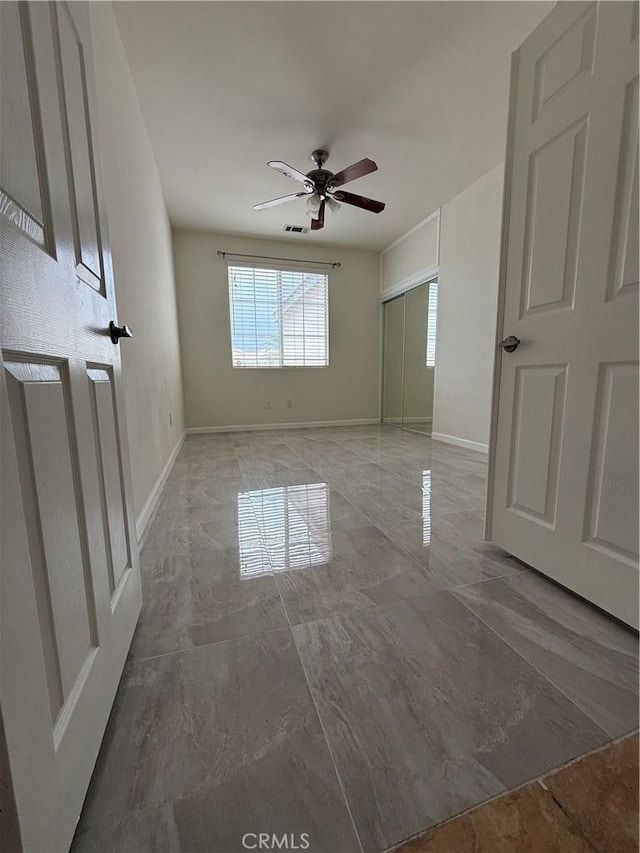 spare room with marble finish flooring, a ceiling fan, and baseboards