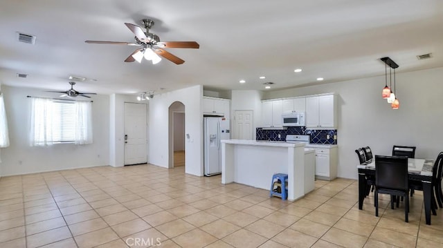 kitchen featuring white appliances, a ceiling fan, arched walkways, backsplash, and white cabinetry