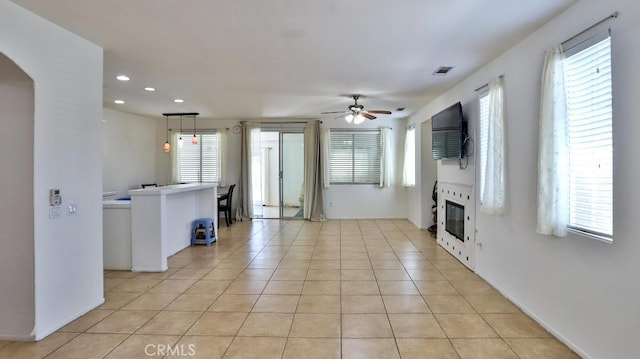 unfurnished living room with ceiling fan, light tile patterned flooring, recessed lighting, plenty of natural light, and arched walkways